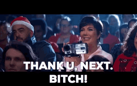 a woman is holding a video camera in front of a crowd and the words thank u next bitch are above her