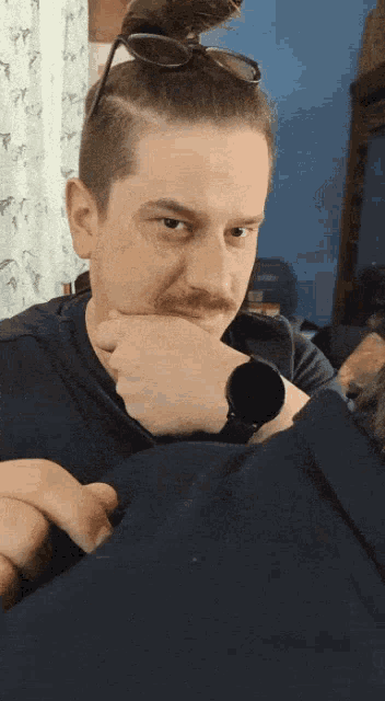a man with a bun on his head is wearing a watch on his wrist