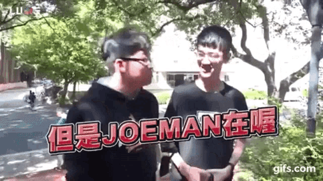 two men are standing next to each other in front of a sign that says joeman on it .