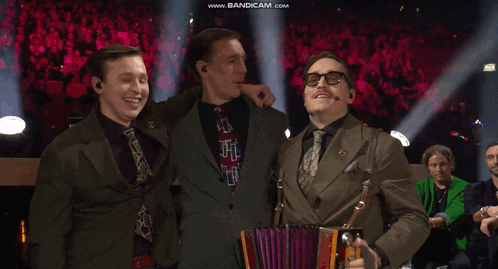 a man in a suit and tie holds an accordion in front of a crowd