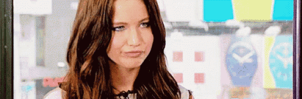 a woman with long brown hair is making a funny face while looking at the camera .