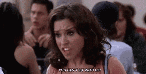a woman is sitting in a crowd of people and making a face .