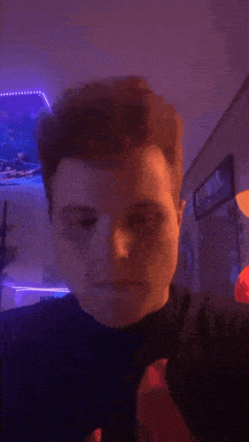 a man is dancing in a room with purple lights