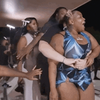 a group of people are standing around a woman in a blue dress who is screaming .