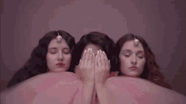 three women are covering their eyes with their hands in a pink dress .