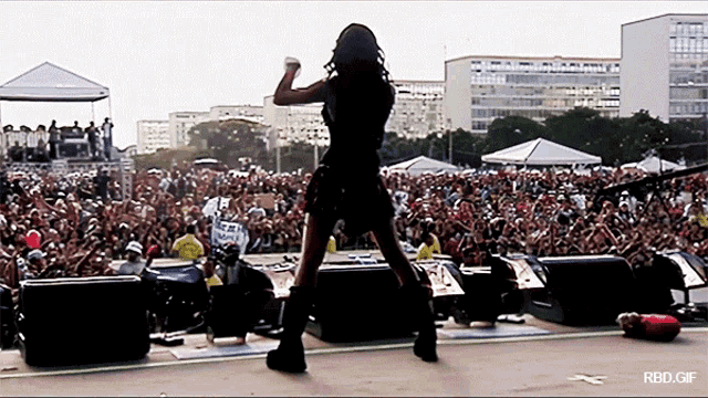 a woman stands on a stage in front of a crowd with a rbd.gif written below her