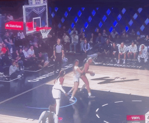 a basketball game is being played on a court with a state farm logo on the hoop