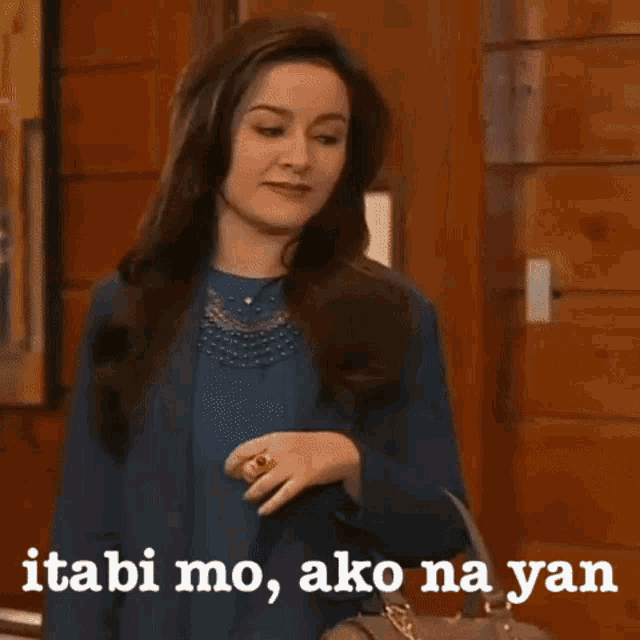 a woman is standing in front of a wooden door with the words " itabi mo ako na yan " written on the bottom