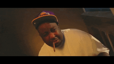 a man wearing a purple lakers hat looks at the camera