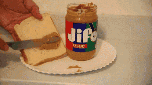 a person spreading jif peanut butter on a piece of bread