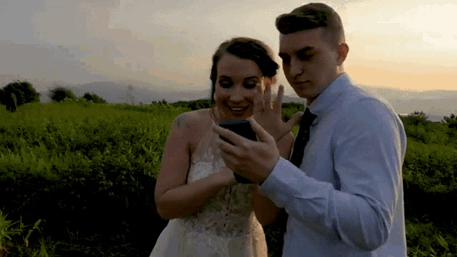a bride and groom looking at a cell phone