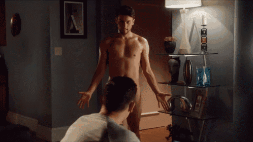 a naked man stands in a living room next to another man