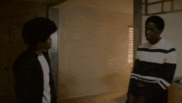 two men standing next to each other in a room