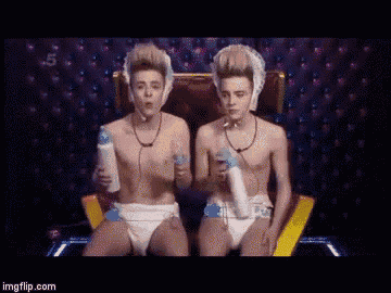 two boys wearing diapers are sitting on a throne holding bottles