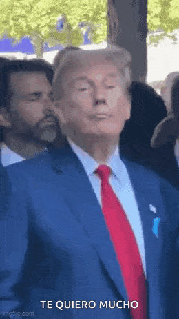 donald trump is wearing a blue suit and red tie and making a funny face .