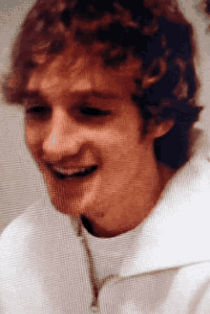 a close up of a person 's face with a white shirt on