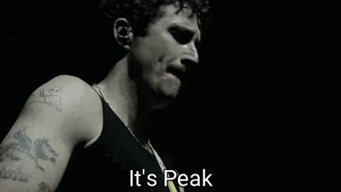 a man with a mustache is singing on a stage and the words `` it 's peak '' are visible .