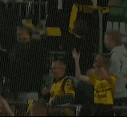 a boy wearing a yellow shirt with the word zahn on it stands in front of a fence