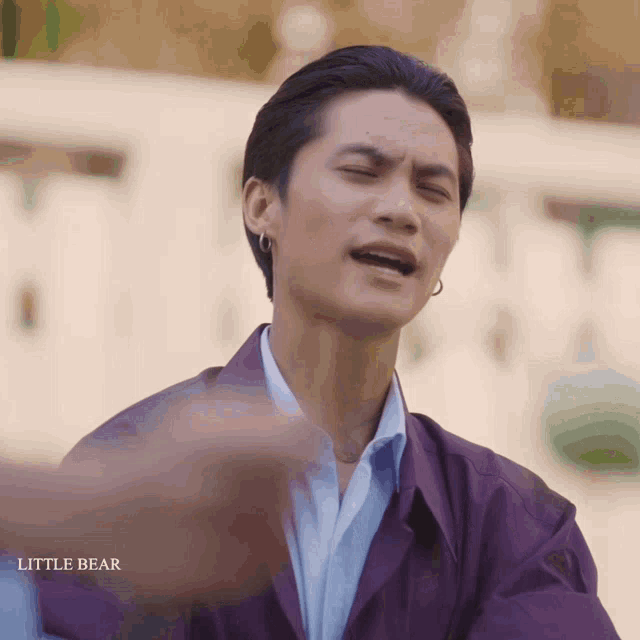 a man in a purple jacket is making a funny face with the words little bear below him