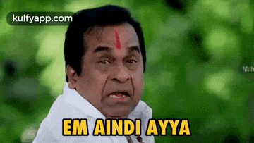 a man with a red circle on his forehead is making a funny face .