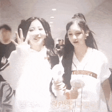 two young women are standing next to each other in a hallway .