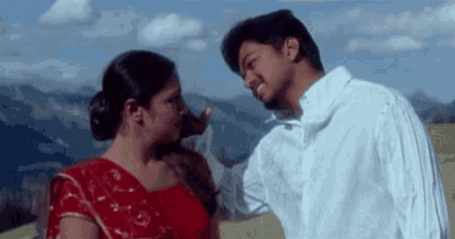a man and a woman are standing next to each other in a field looking at each other .