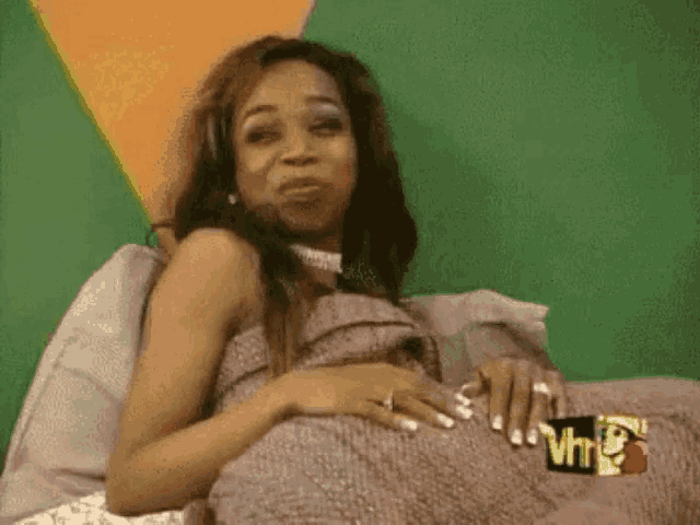 a pregnant woman is laying on a bed with a pillow and a sign that says vh1 .