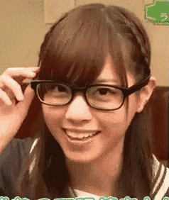 a young woman wearing glasses is smiling while adjusting her glasses .
