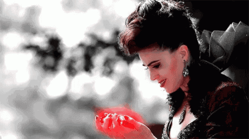 a woman is holding a red object in her hands and it is glowing red .
