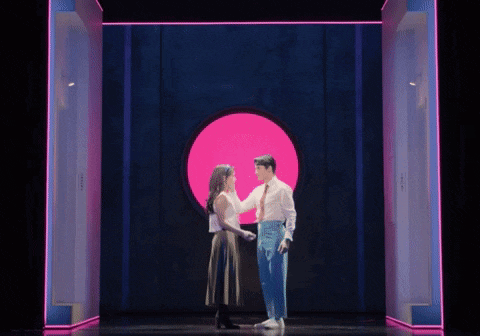 a man and a woman are dancing in front of a pink circle .