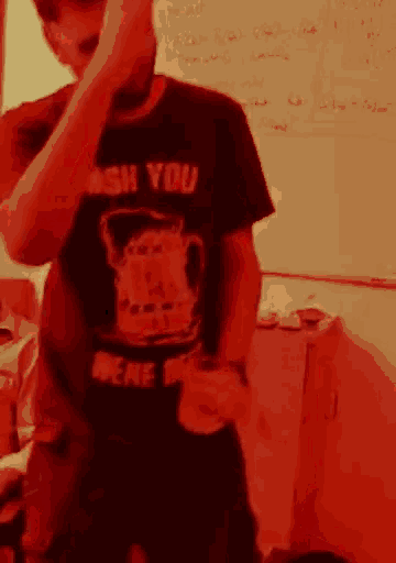 a man wearing a shirt that says " wish you were here " is standing in front of a white board