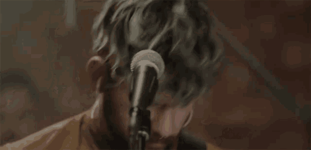 a close up of a man singing into a microphone .