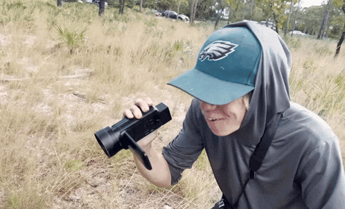 a man wearing a hat that says eagles is holding a camera
