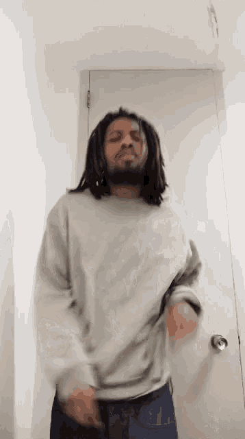 a man with dreadlocks is wearing a grey sweater