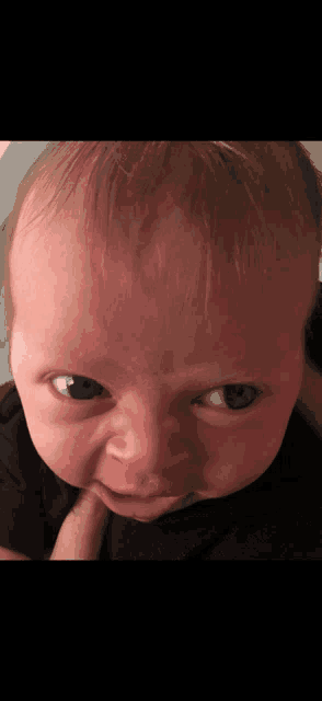 a close up of a baby 's face with a black shirt on