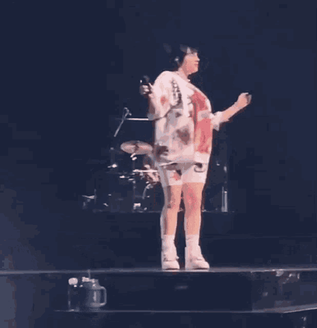 a woman is standing on a stage wearing a shirt that has the letter k on it