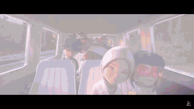 a group of people are sitting on a bus and one of them is wearing a hat