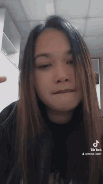 a woman with long hair is making a funny face with her hand