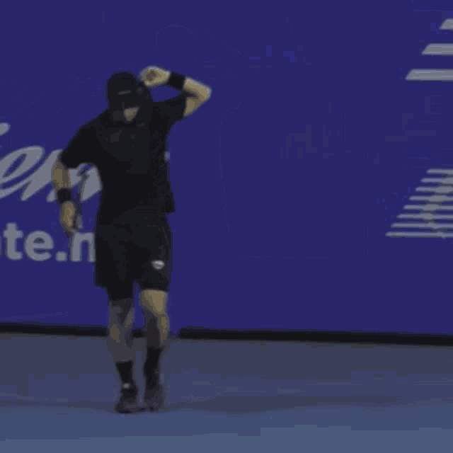 a man is holding a tennis racquet in front of a blue wall that says ente.n