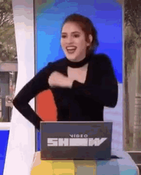 a woman is sitting at a table with a box that says video show on it