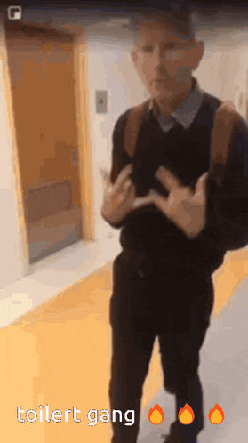 a man is standing in a hallway with the words toilet gang on the bottom right