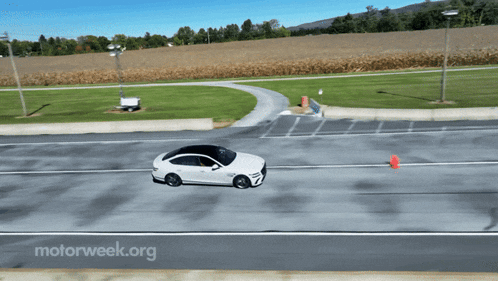 a white car is driving down a road with motorweek.org written in the corner