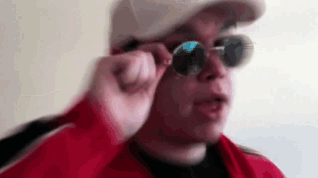 a blurry picture of a man wearing sunglasses and a hat .