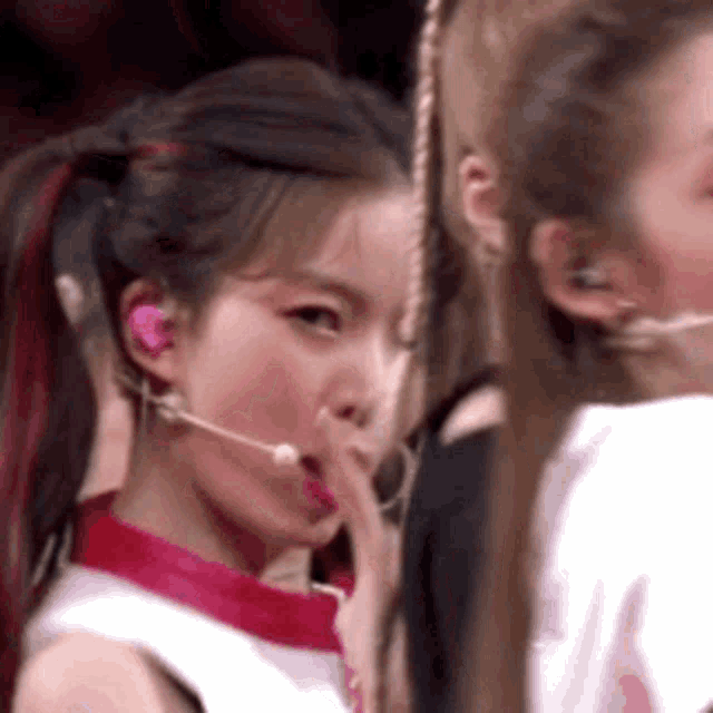 a woman with a microphone in her ear is covering her mouth .