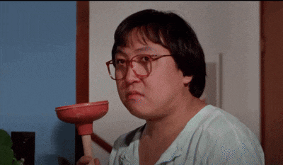 a man with glasses is holding a red plunger in his hand