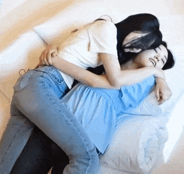 two women are hugging each other in bed .