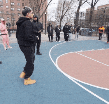 a group of people standing on a basketball court with one man wearing a black hoodie with the letter r on it