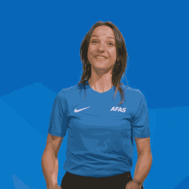 a woman wearing a blue shirt that says afas is pointing up