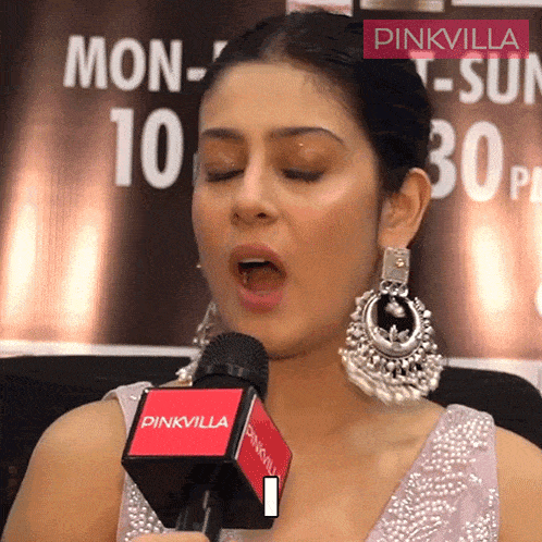 a woman speaking into a pinkvilla microphone while wearing earrings