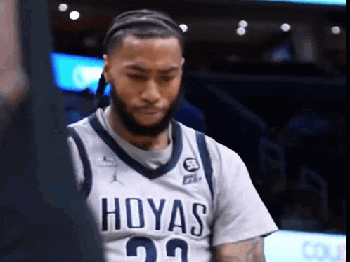 a man wearing a hoyas jersey is looking down